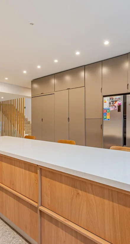 Cocina con muebles de madera y barra blanca